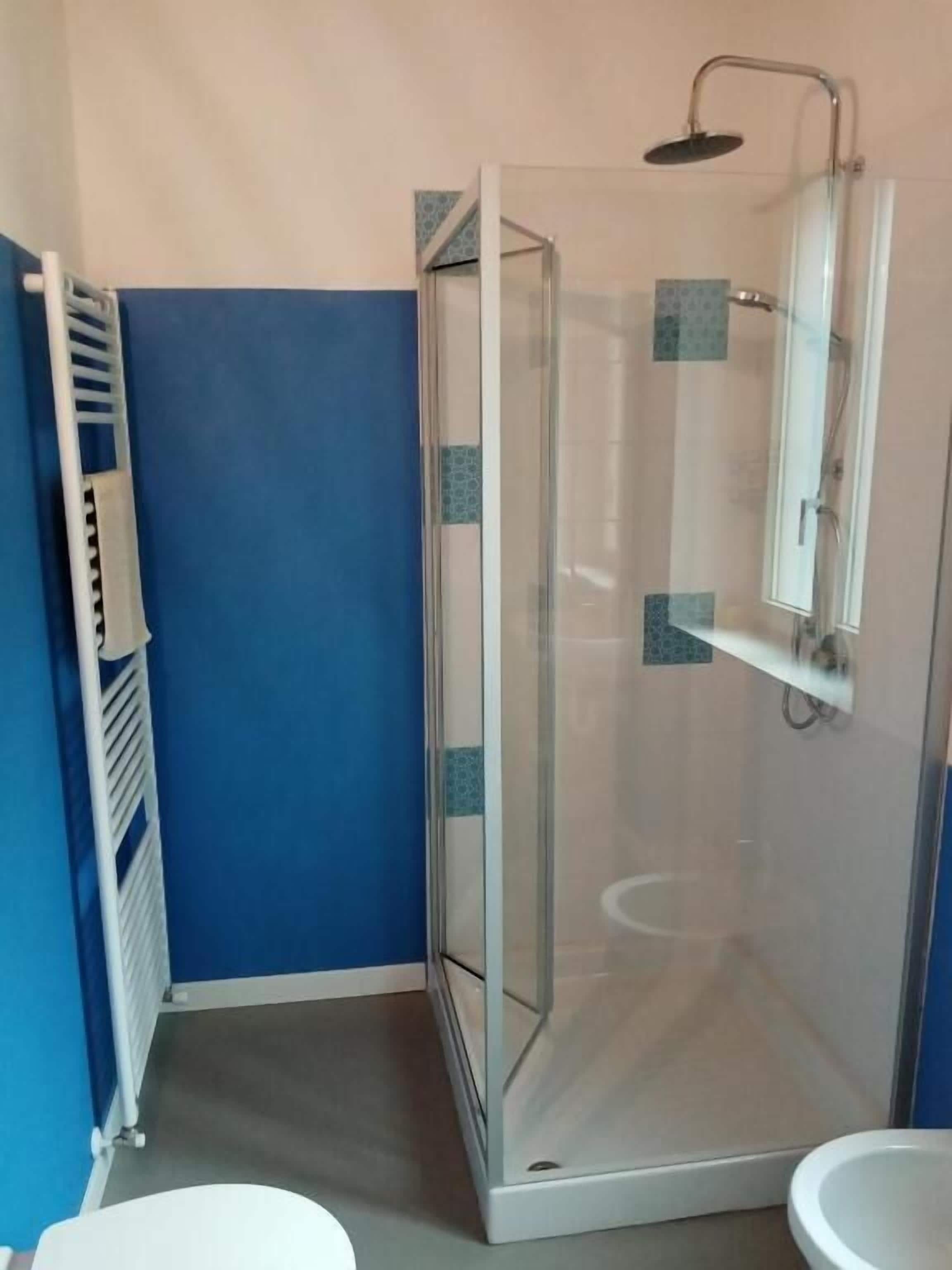 A bathroom with a glass-enclosed shower, a white sink, and a towel rack.