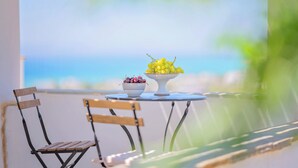 A table with two bowls of fruit and two wooden chairs.