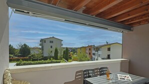 Ein Balkon mit Tisch, Stühlen, einer Statue und Blick auf Gebäude.