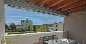 Un balcon avec une table et des chaises, une statue et une vue sur les bâtiments.