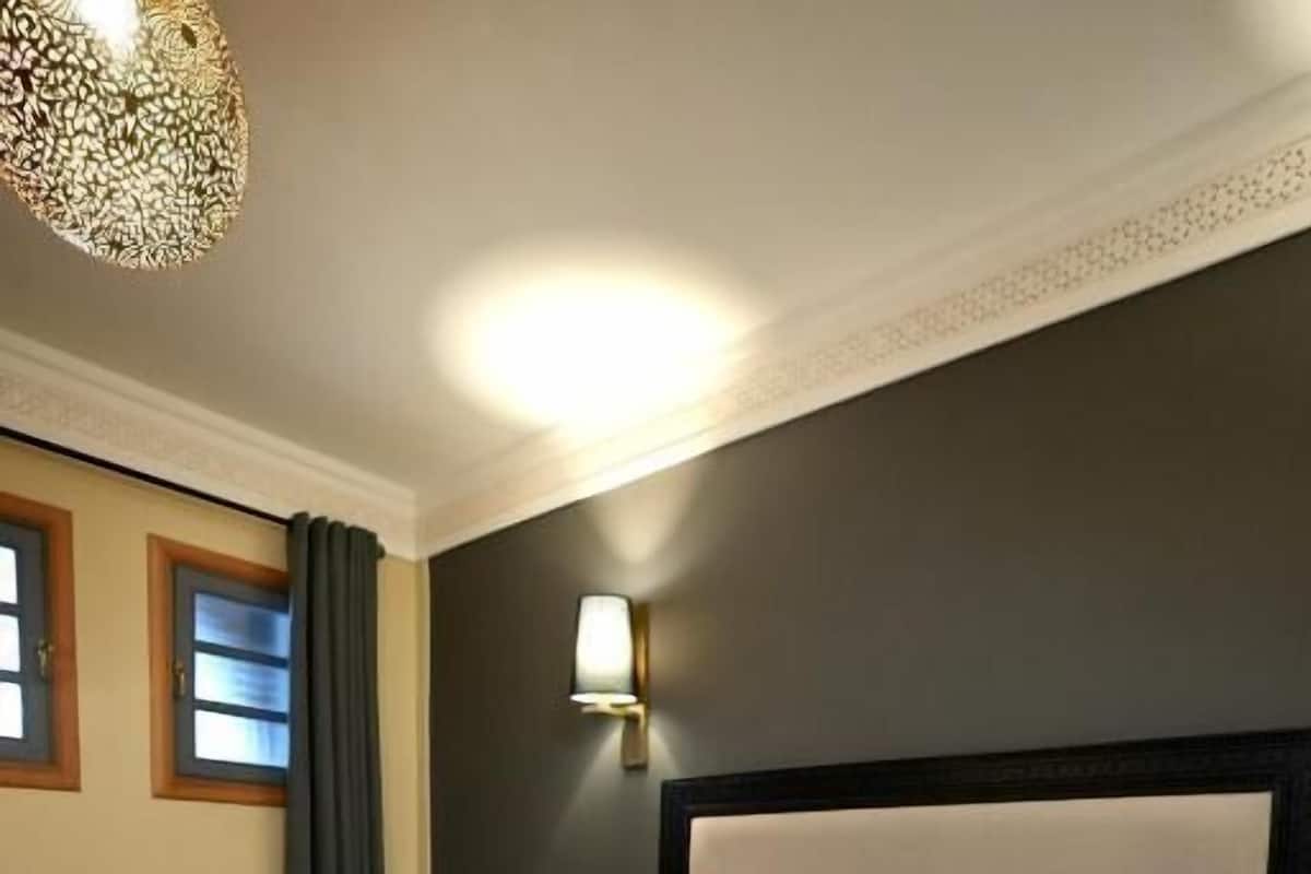 Habitación de hotel con una cama grande, una mesita de noche, una lámpara y vistas al exterior.