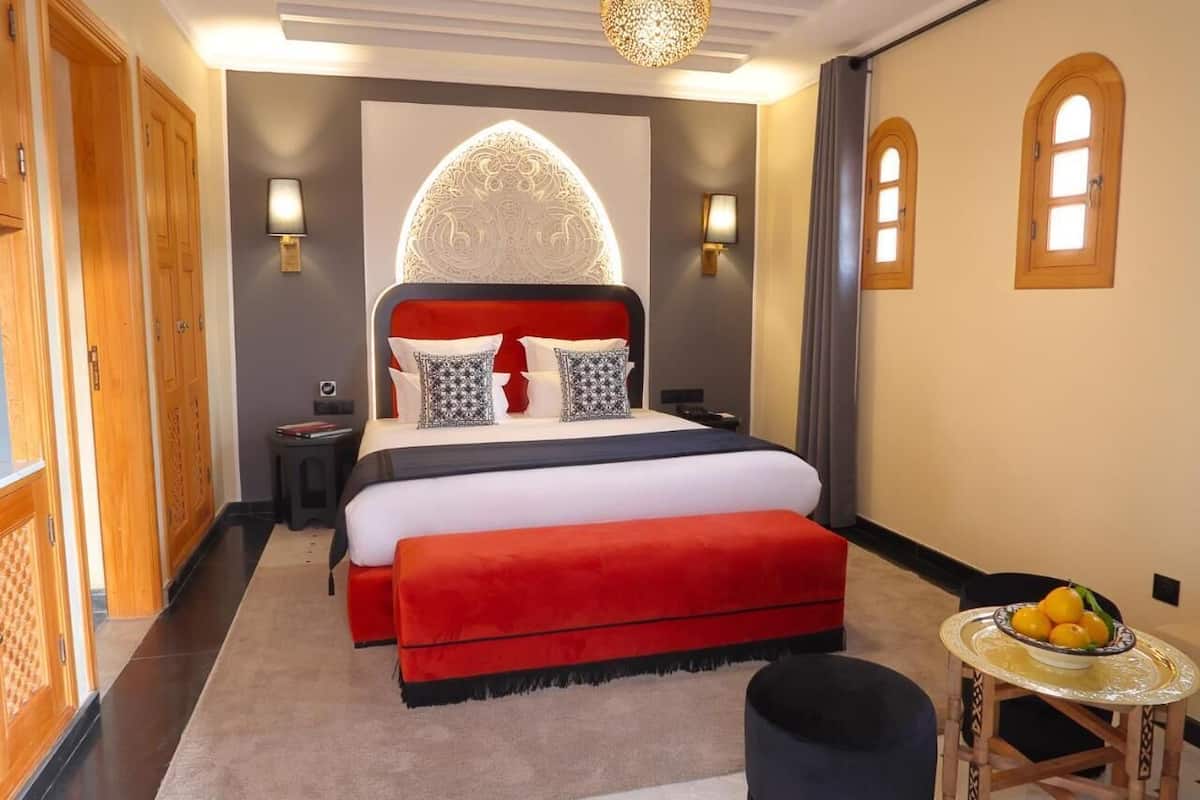 Un dormitorio con una cama grande, una mesita de noche, una lámpara y un adorno en la pared.