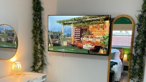 Un dormitorio con cama, escritorio, silla, televisor y espejo.