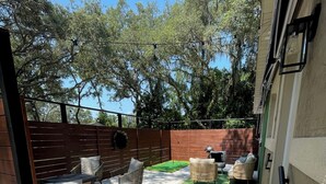 Un patio con mobiliario exterior, una terraza de madera y un césped.