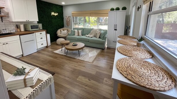 Una cocina moderna con armarios blancos, un microondas y una pared verde con un letrero de neón.