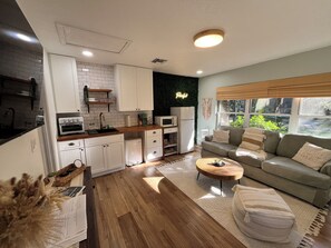 Una cocina moderna con armarios blancos, encimera de madera y horno empotrado.