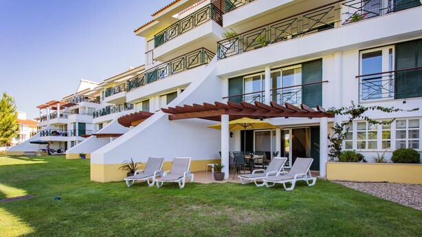 A multi-story hotel with outdoor seating areas, a covered patio, and a pool.