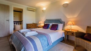 A bedroom with a bed, bedside tables, a chair, and a bathroom visible through an open door.