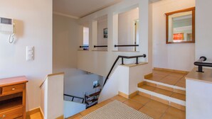 A modern interior with a staircase, a wooden bench, and a telephone on the wall.