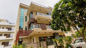 Un edificio residencial de varios pisos con balcones, una escalera y un árbol en primer plano.