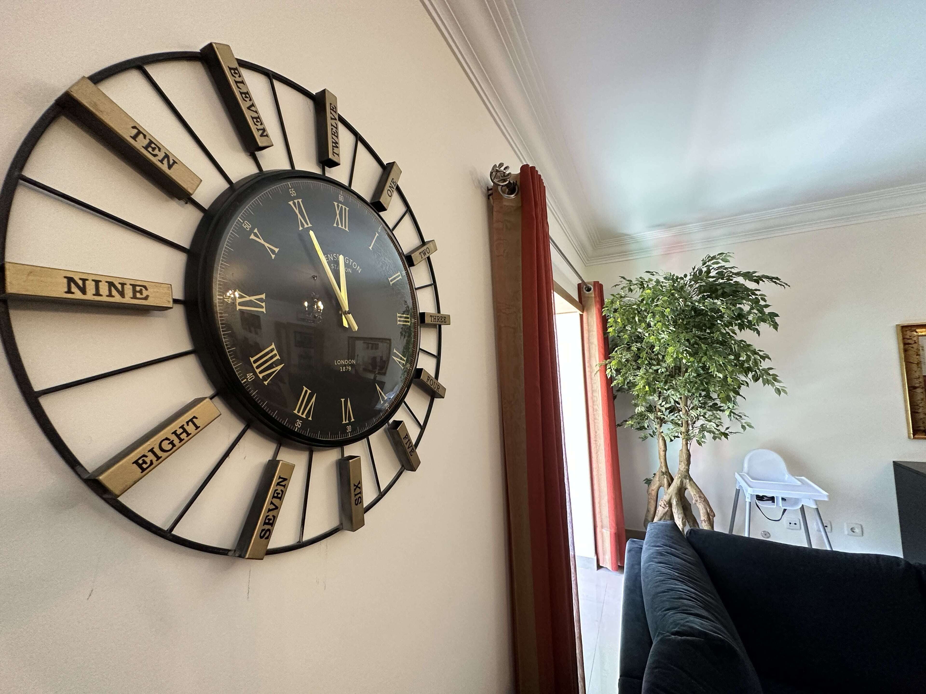 A wall-mounted clock with Roman numerals and hour markers labeled with numbers.