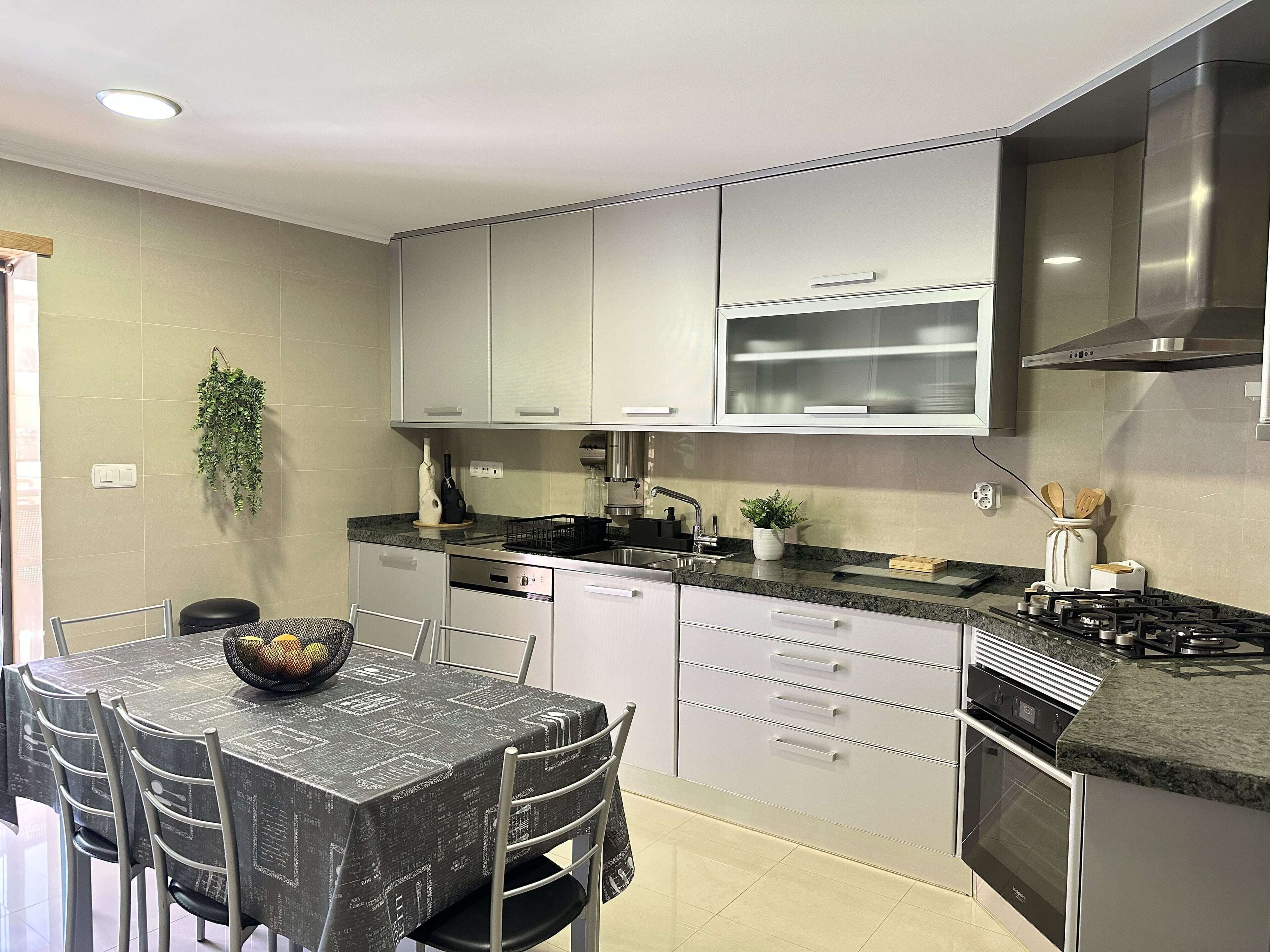 A modern kitchen with white cabinets, a black countertop, and stainless steel appliances.