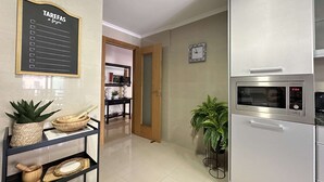 A modern kitchen with a built-in microwave and refrigerator, a wooden console table with decorative items, and a hallway leading to another room. - Ameijeira Lagos Apartment (Lagos)