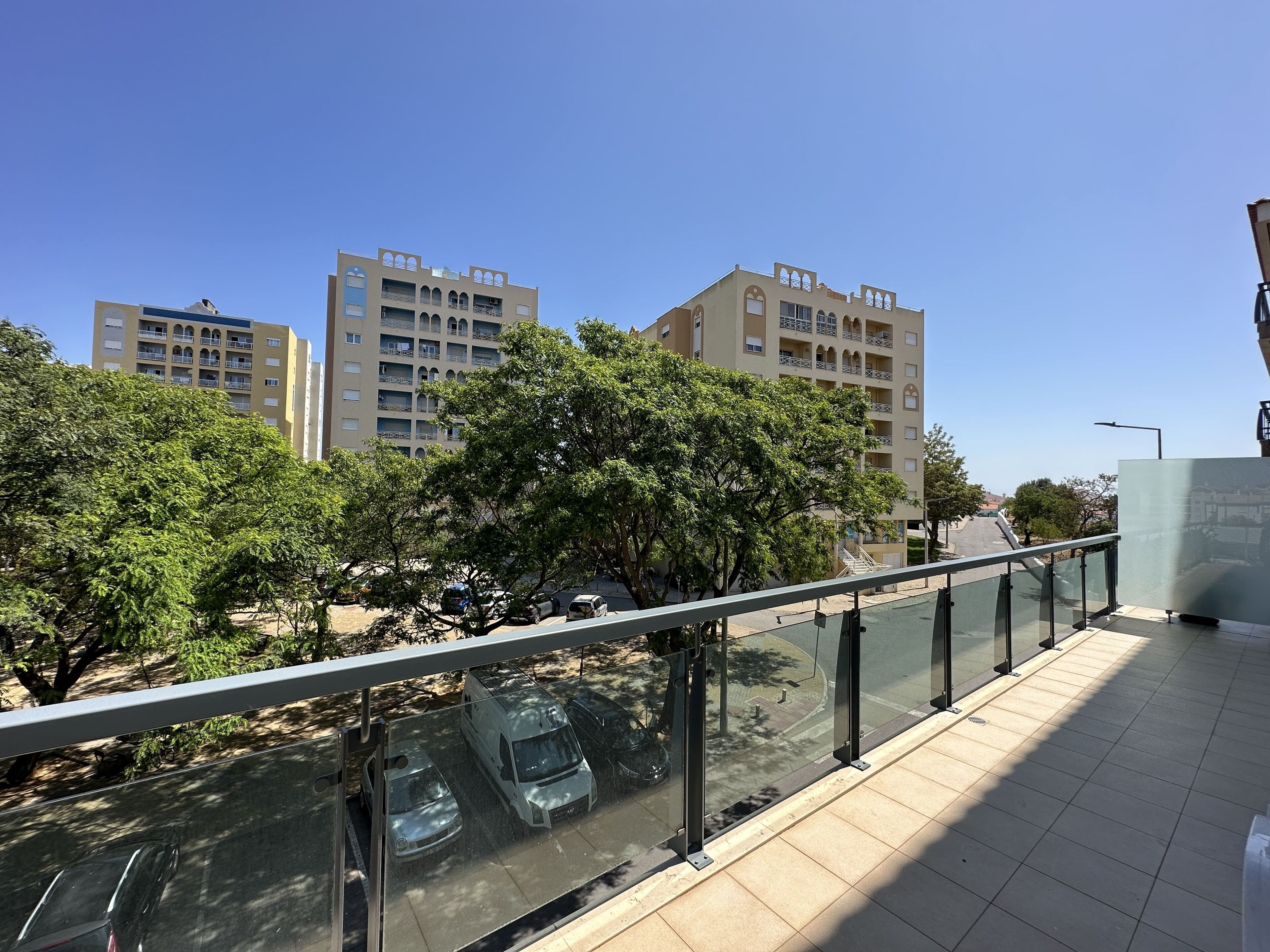 Un bâtiment moderne doté d’une balustrade en verre donnant sur un parking.