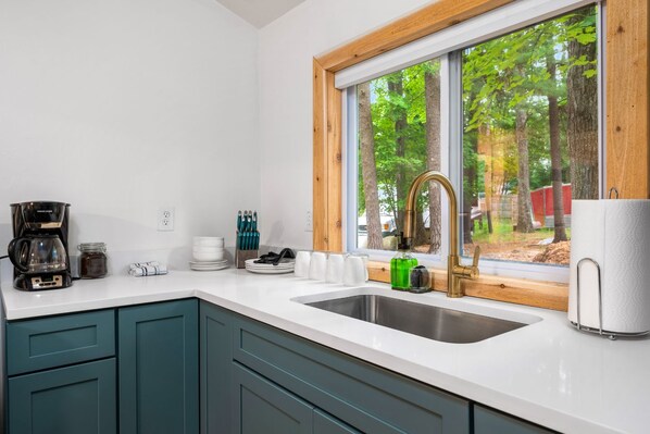 A modern kitchen with a large window, a coffee maker, and a sink.