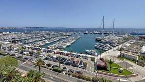 A marina with numerous boats docked, a parking area, and a clear view of the sea. - (102) Le superbe au Palais (Vallauris)