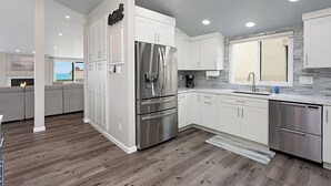 Une cuisine moderne avec des meubles blancs, des appareils en acier inoxydable et un plancher en bois.