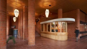 A spacious lobby with brick columns, a curved reception desk, and hanging chandeliers. - Parkhotel Wallberg (Volketswil)