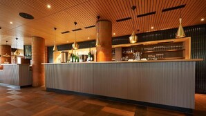 A modern bar area with a central counter, wooden ceiling, and ambient lighting. - Parkhotel Wallberg (Volketswil)