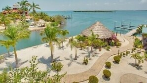 A resort with a beach, palm trees, a thatched-roof hut, and a dock. - Magnificent Belize Townhouse-Pool-Private Island (Placencia)