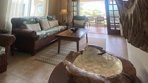 A spacious living room with a ceiling fan, a sofa set, a coffee table, and a large rock sculpture. - Magnificent Belize Townhouse-Pool-Private Island (Placencia)