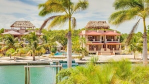 A resort with multiple buildings, a swimming pool, and palm trees. - Magnificent Belize Townhouse-Pool-Private Island (Placencia)