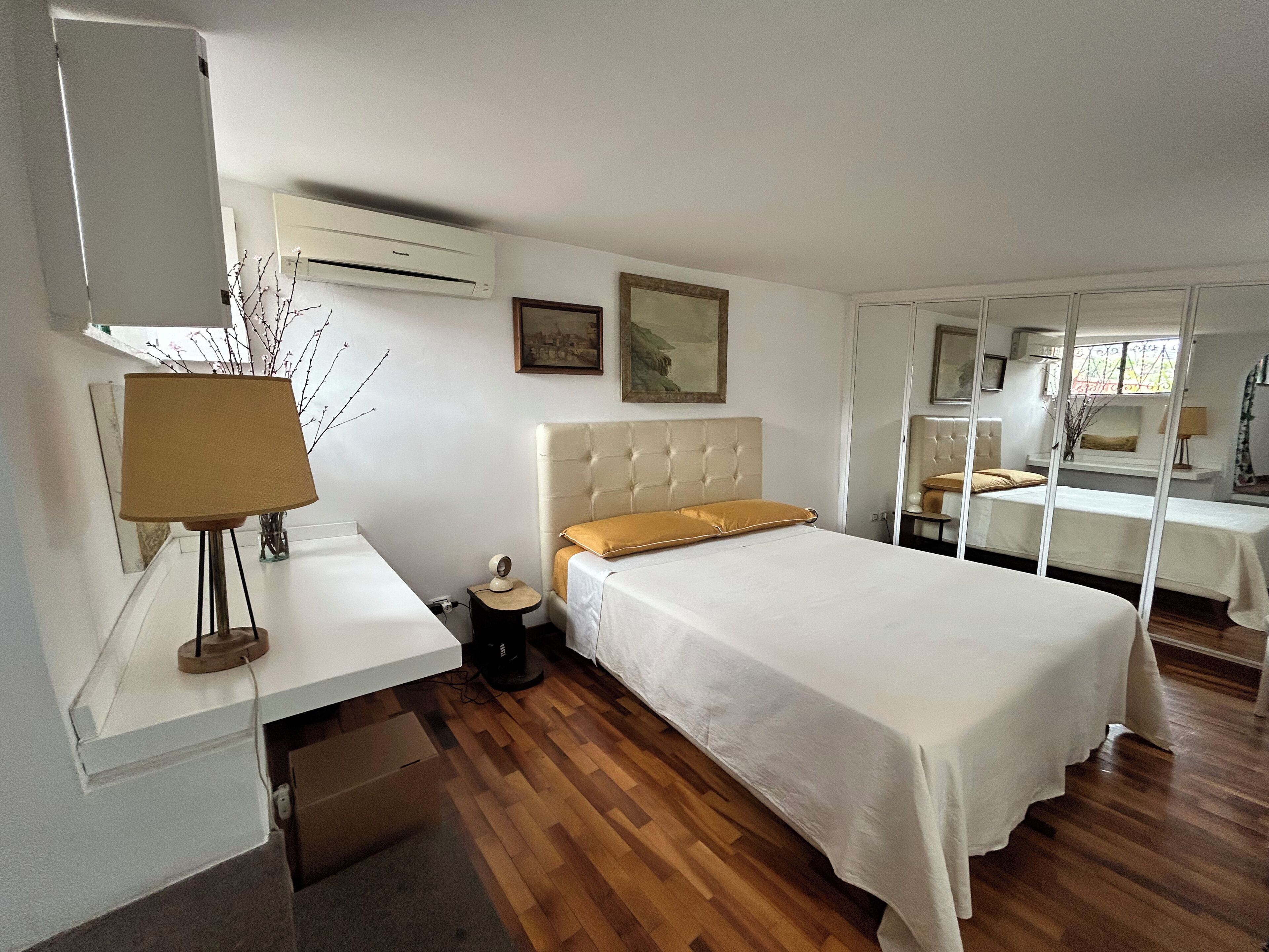 Ein Hotelzimmer mit einem Einzelbett, einem Nachttisch, einer Lampe und einem Spiegel.