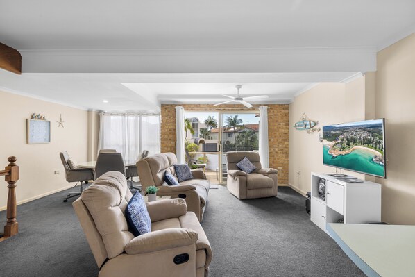 Ein Wohnzimmer mit einer Sofagarnitur, einem Fernseher und Blick ins Freie.