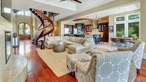 A spacious living area with a spiral staircase, a kitchen, and a dining area. - Luxurious oceanfront home with private pool with spa (Hilton Head Island)