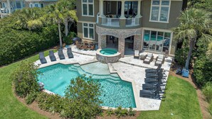 A two-story house with a swimming pool, outdoor seating, and a covered patio. - Luxurious oceanfront home with private pool with spa (Hilton Head Island)