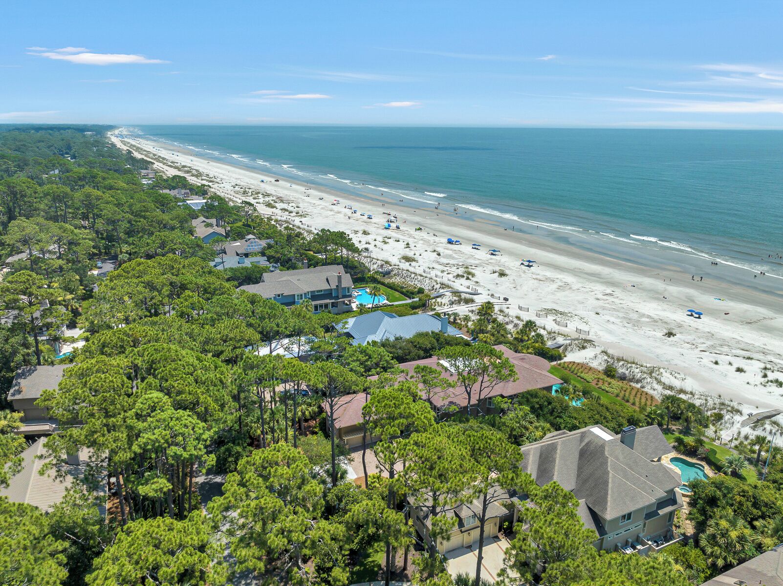 A coastal residential area with houses, a beach, and a clear view of the ocean.