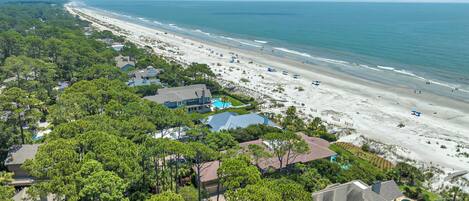 A coastal residential area with houses, a beach, and a clear view of the ocean.