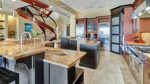 A modern kitchen with granite countertops, stainless steel appliances, and a wooden staircase. - Luxurious oceanfront home with private pool with spa (Hilton Head Island)
