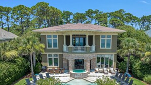 A two-story house with a large front yard, a swimming pool, and a covered patio area. - Luxurious oceanfront home with private pool with spa (Hilton Head Island)