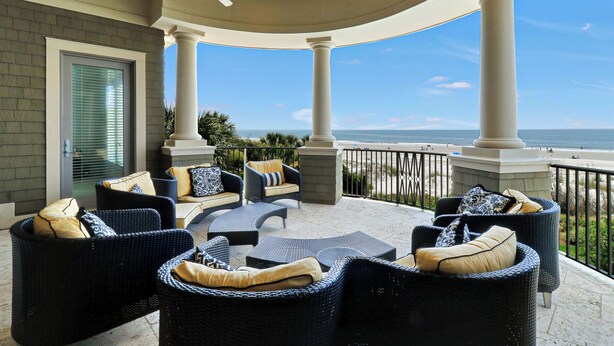 A covered outdoor seating area with wicker furniture and a view of the beach. - Luxurious oceanfront home with private pool with spa (Hilton Head Island)