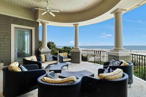 A covered outdoor seating area with wicker furniture and a view of the beach.