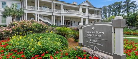 A large, two-story building with multiple balconies and a well-maintained garden with red and yellow flowers.