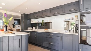 Een moderne keuken met grijze kastjes, een centraal eiland en een ingebouwde oven.
