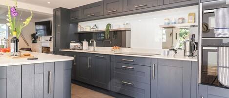 A modern kitchen with grey cabinetry, a central island, and a built-in oven.