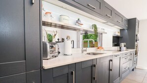 Een moderne keuken met donkere kastjes, een roestvrijstalen spoelbak en een broodrooster.