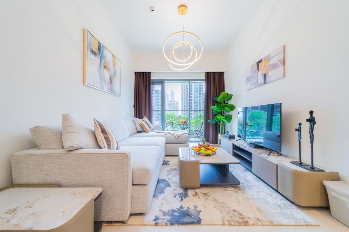 A modern living room with a sofa, coffee table, TV, and artwork.
