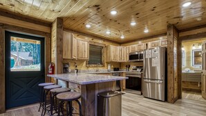 A modern kitchen with wooden cabinetry, stainless steel appliances, and a central island with bar stools.