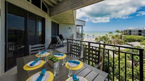 A balcony with a table set for four, overlooking a beach. - **SUITE SANCTUARY** Oceanfront Condo & Pool + Last Key White Glove Service... (Key West)