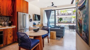 A modern kitchen with wooden cabinets, a stainless steel refrigerator, and a dining area with a round table and blue chairs. - Romantic Zone Penthouse w/Ocean Views (Puerto Vallarta)