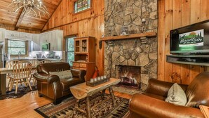 Een gezellig interieur van een chalet met een stenen open haard, lederen meubels en een keukenhoek.