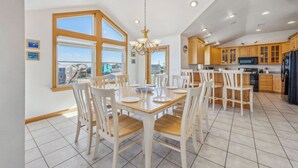 Eine geräumige Küche mit Holzausstattung, ein Essbereich mit weißen Stühlen und große Fenster mit Blick auf die Stadt.