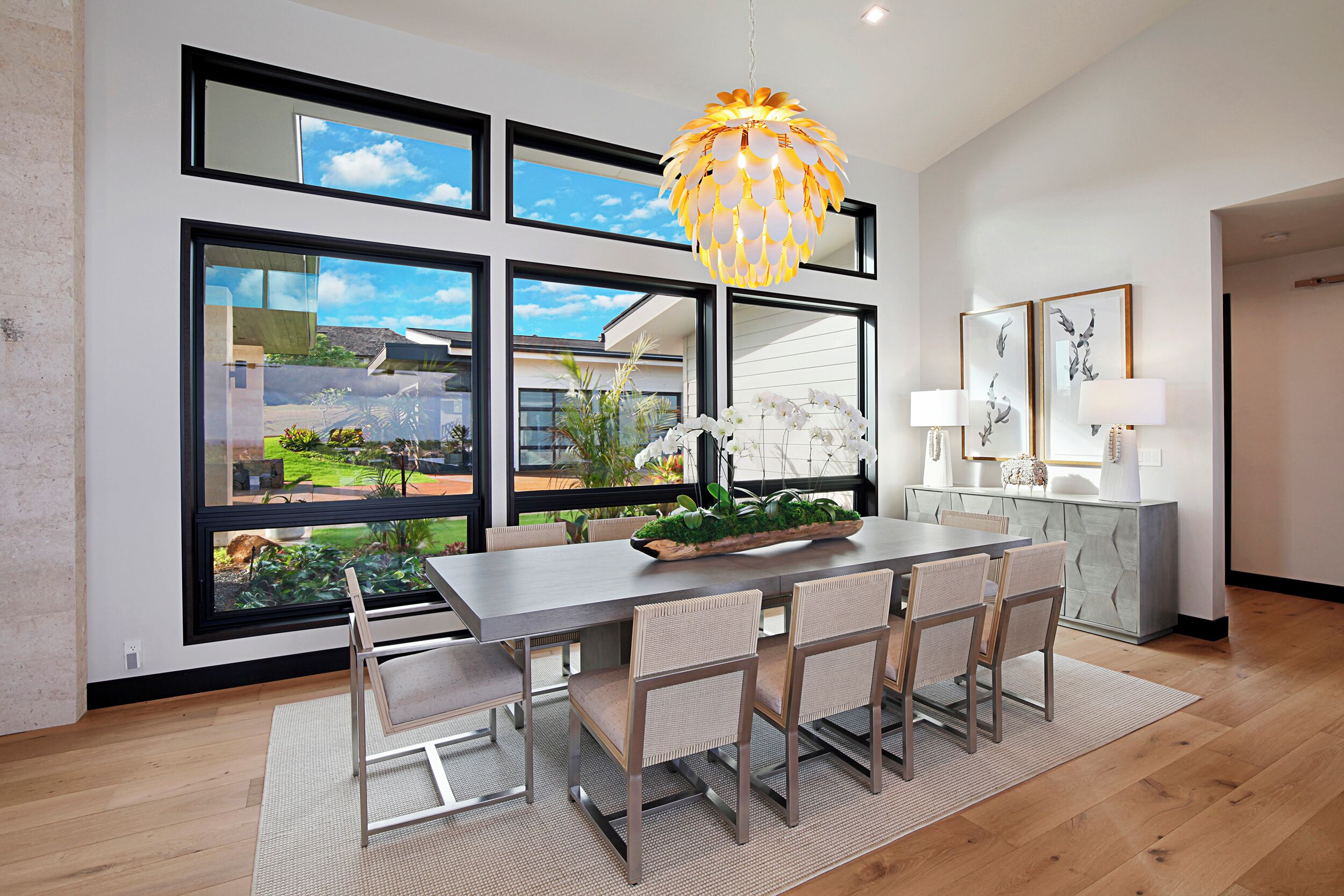 A modern dining area with a large table, chairs, and a decorative hanging light fixture.