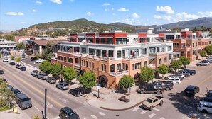 A multi-story building with a central courtyard, surrounded by parked cars and trees. - Sprawling Condo | Central Downtown | Free Shuttle (Steamboat Springs)