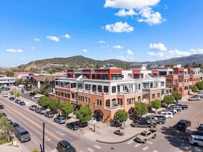 Un edificio de varios pisos con un patio central, rodeado de coches estacionados y árboles.
