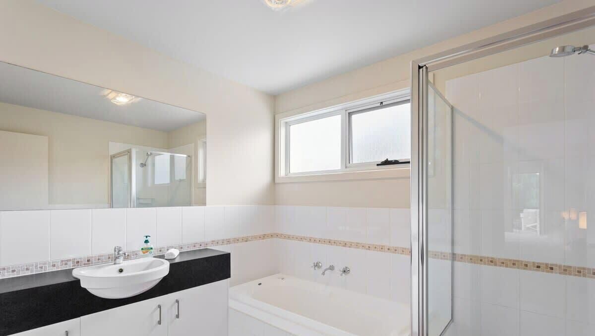 A bathroom with a sink, mirror, bathtub, and shower.
